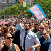 Mamdani showing his support at pride in a sea of rainbows and people, Mamdani holds a trans flag.