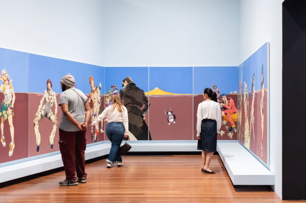 museum goers browse a floor to ceiling installation that wraps around a wall and corner