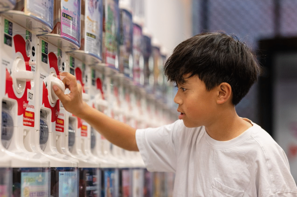 a boy runs his hands along the gashapon machines